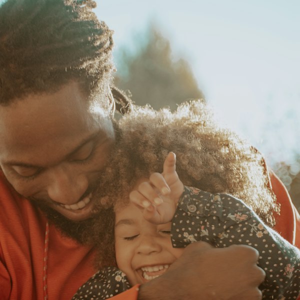 A dad hugging his laughing daughter